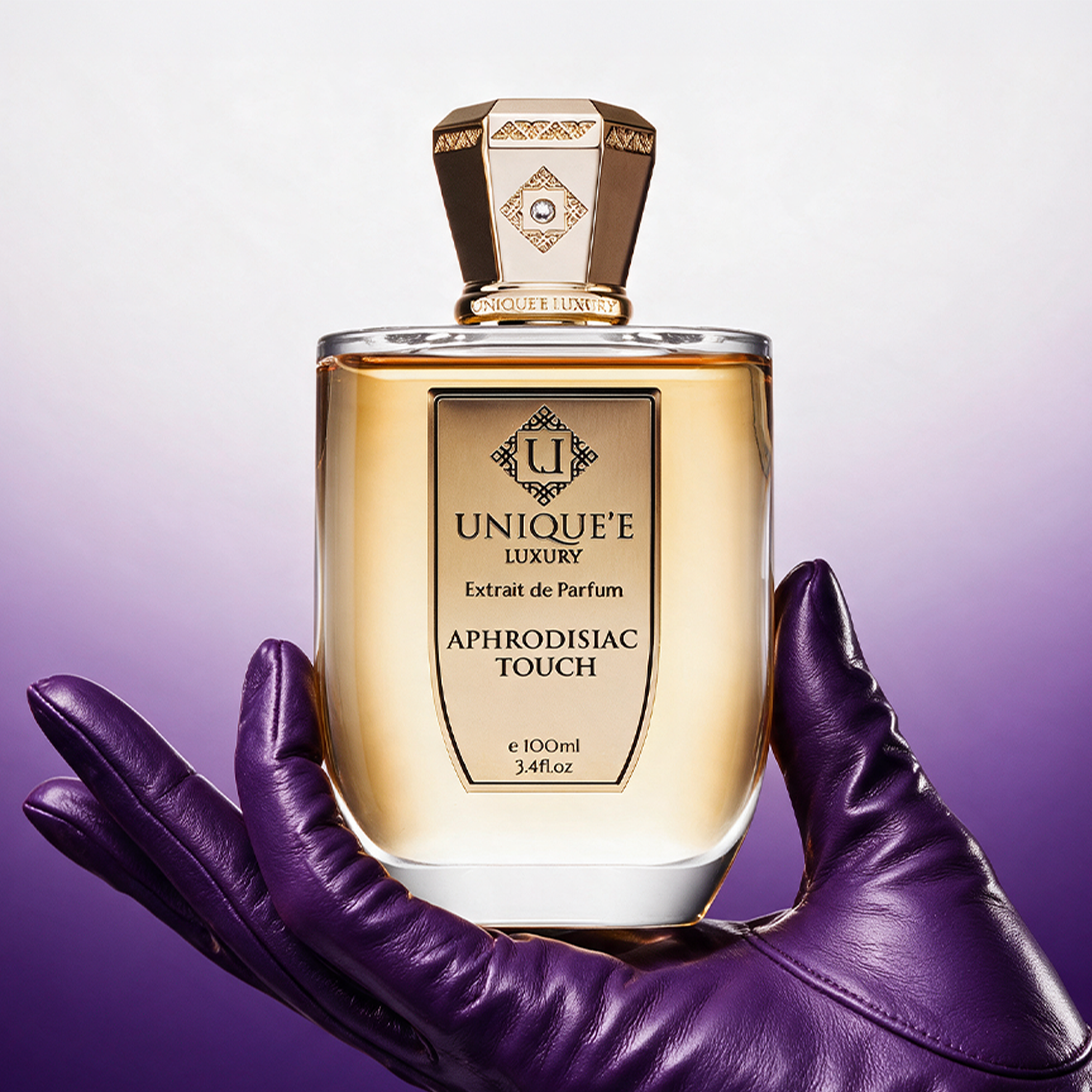 A bottle of 'APHRODISIAC TOUCH' perfume by Unique'e Luxury with a gold-colored liquid inside, displayed against a plain background.