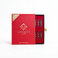 A luxury perfume discovery set in a red box, with the lid standing open next to the box interior showing several slim black perfume strips with gold lettering.